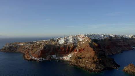 Slow-panoramic-aerial-panning-shot-of-Oia-in-Santorini,-Greece-during-sunset,-4K-prores