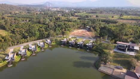 Aerial-Drone-Footage-of-a-Hotel-and-Resort-with-Villas-on-the-Lake-with-Beautiful-Scenic-Background-of-Forest-Trees-and-Mountainous-Background-in-Thailand