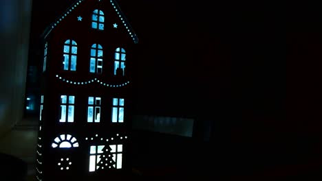 Illuminated-fancy-miniature-doll-house-with-ambient-blue-lighting-in-cut-out-windows-at-night