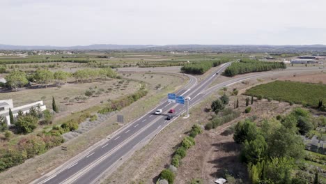 Cars-entering-the-town-of-Clermont-l'Hérault-in-Southern-France,-Aerial-dolly-left-shot