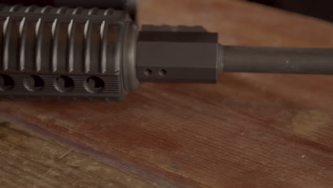 Close-dolly-over-AR-15-barrel-on-a-wooden-surface