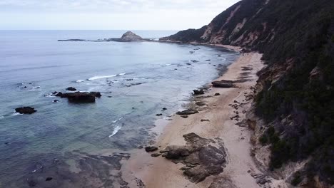 Aerial-drone-shot-ascending-up-to-reveal-the-calm-ocean-waters-and-beach-coastline-at-Sedgefield,-a-popular-travel-destination-along-the-Garden-Route-in-the-Western-Cape,-South-Africa