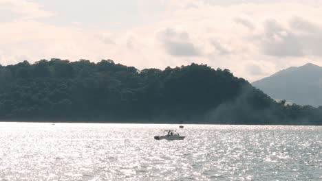 Kleines-Fischerboot,-Das-An-Einem-Bewölkten,-Warmen-Morgen-Vom-Damm-Von-Amador,-Einem-Grünen-Waldland-In-Panamas-Sommerzeit,-über-Das-Wasser-Des-Panamakanals-Navigiert