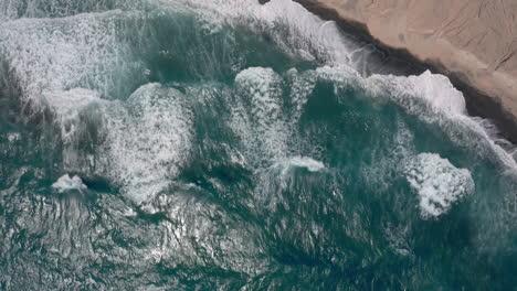 Aerial:-Big-waves-in-Vlychada-beach-of-Santorini,-Greece,-4K-prores