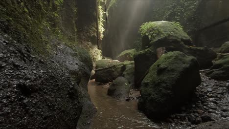 a-small-stream-in-a-narrow-canyon-with-sunbeams-shining-through-the-mist