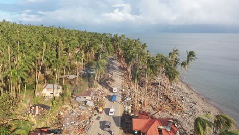 Aerial-View-Of-Vehicles-Driving-Pass-By-Destroyed-Houses-After-Typhoon-Odette-In-Southern-Leyte,-Philippines