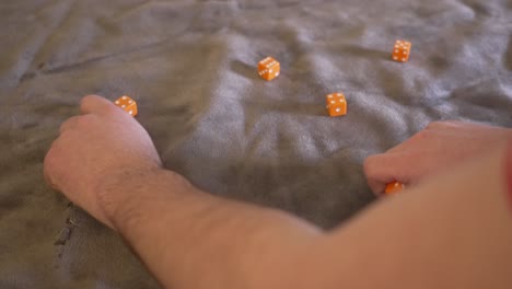Ten-orange-dice-being-rolled-in-slow-motion-onto-a-gray-felt-platform-cover