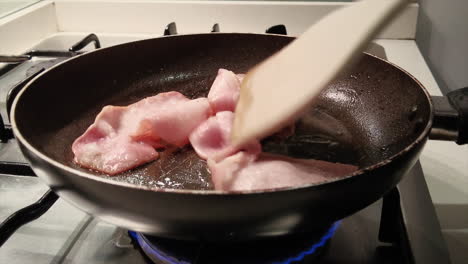 Bacon-being-cooked-up-in-a-frying-pan-with-visible-oil-splatter
