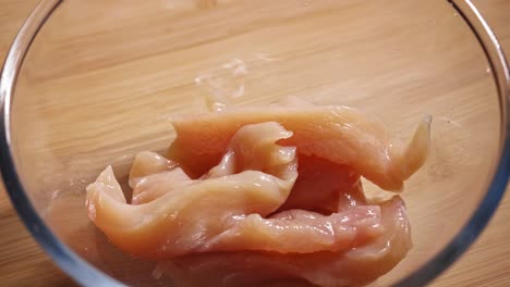 Close-up-View-Pieces-of-Chicken-Breast-Fillet-Added-to-Glass-Bowl