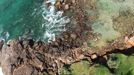 Aerial-top-down-spinning-over-rocky-shore-and-turquoise-sea-with-waves-at-daytime-in-Mirissa-beach,-Sri-Lanka
