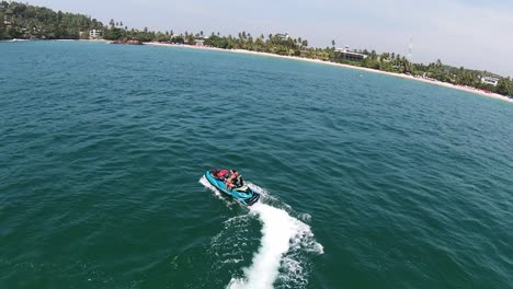 Aerial-Drone-Slow-Motion-Of-Man-Doing-Water-Sports-On-Jet-Ski-Off-Sri-Lanka-Beach-In-Blue-Ocean