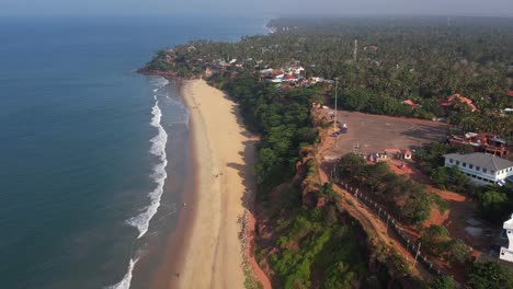 Aerial-shot-of-Varkala-beach-with-trees-and-buildings-in-the-shore
