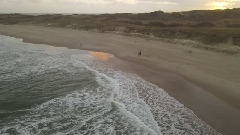 People-walking-on-beach-at-sunset,-Playa-La-Viuda