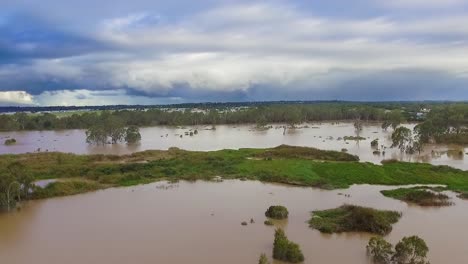 Queensland,-NSW,-Australien,-Überschwemmungen-Im-Februar---Rückwärtsbewegung-über-überschwemmtes-Buschland-Und-Schmutzig-Braune-Fluten-In-Einem-Vorort-Von-Brisbane,-Unter-Stürmischem-Und-Bedrohlichem-Himmel