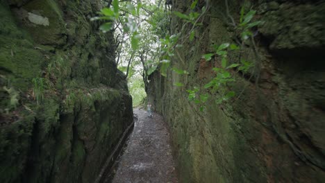 Mujer-Caminando-A-Través-De-La-Roca-Recortada-Vía-Fluvial-Levada-En-Madeira,-Viaje-De-Viaje