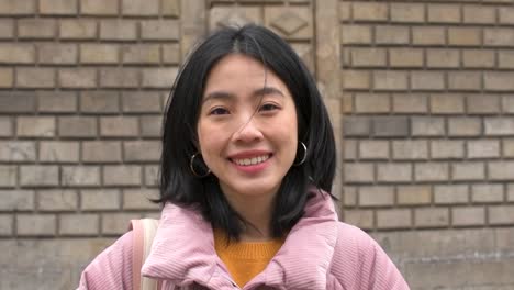 Zeitlupe-Eines-Süßen-Asiatischen-Studentenmädchens-Mit-Rucksack,-Das-Die-Kamera-Anschaut,-Während-Es-Lächelt
