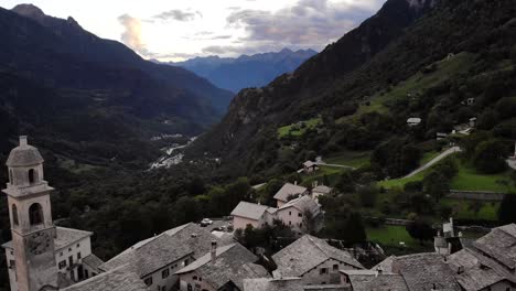 Aerial-flyover-over-the-rooftops-of-the-historical-village-of-Soglio-in-the-Bregaglia-region-of-Grissons,-Switzerland-with-a-view-of-the-old-church-and-Breagaglia-valley