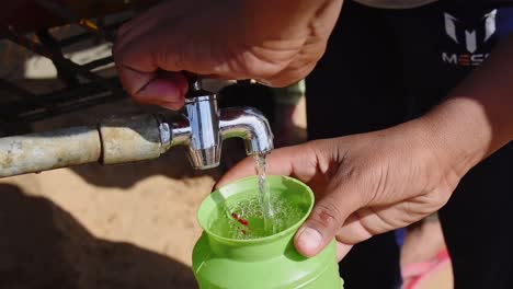Eine-Person-Füllt-Einen-Plastikkrug-Mit-Trinkwasser-Aus-Dem-Wassertanker-Am-Veranstaltungsort-Des-Wüstenfestivals