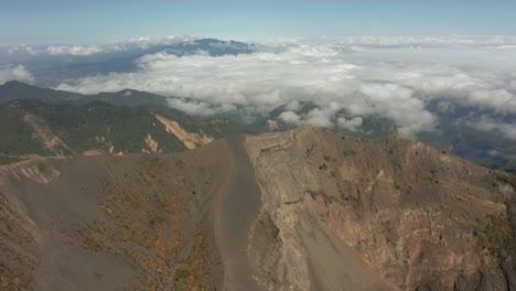 Steep-crater-wall-of-Irazu-volcano-in-Costa-Rica,-landscape-covered-in-clouds-in-background,-aerial