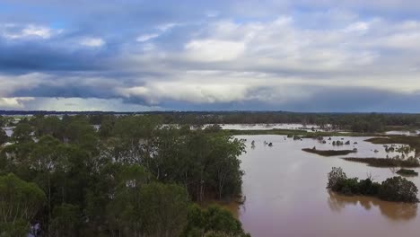 Queensland,-NSW,-Australia,-February-floods---dramatic-aerial-drone-shot-travelling-over-flooded-bushland-and-over-inundated-flood-plains-in-Brisbane,-under-dramatic-stromy-skies