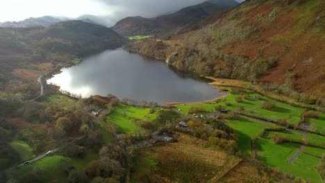 Drone-flying-over-banks-of-Llyn-Gwynant-in-Snowdonia,-Wales-in-UK