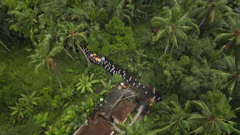 White-clothed-Bali-people-walking-on-street-during-Galungan-ceremony-in-lush-green-jungle
