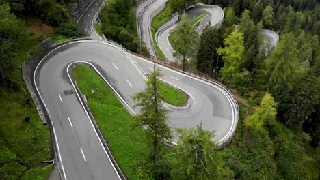 Aerial-flyover-over-the-turns-of-Maloja-pass-in-Engadin,-Switzerland-with-a-pan-up-revealing-the-curves-of-the-road