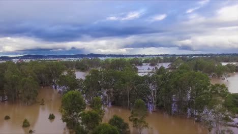 Queensland,-NSW,-Australia,-February-floods---stunning-aerial-drone-shot-travelling-over-flooded-bushland-and-over-inundated-flood-plains-in-Brisbane,-under-dramatic-stromy-skies