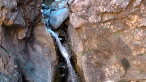 Eaton-Canyon-Falls,-waterfall-pouring-down-between-rock-formation,-aerial-rising,-Pasadena