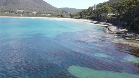 Drohne-Aus-Der-Luft-über-Tropischem-Blauem-Wasser,-Das-Felsen-Mit-Mustern-Auf-Dem-Pflaster-In-Tasmanien-Zeigt