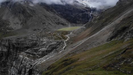 Aerial-flyover-towards-Lagh-da-Caralin-glacial-lake-underneath-Palu-glacier-on-a-cloudy-day-in-the-Swiss-Alps-near-Engadin
