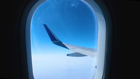 Airplane-wing-view,-mid-air-through-porthole