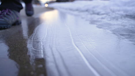 Woman's-boot-walking-in-slow-motion,-cracking-ice-on-sidewalk