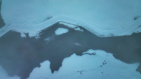 Vista-Superior-De-Una-Mujer-Bañándose-En-Un-Río-Geotérmico-En-Invierno-En-El-Valle-De-Reykjadalur,-En-El-Sur-De-Islandia