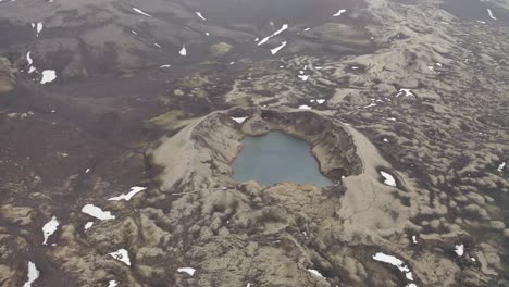 Aerial-View-Of-Tjarnagigur-Crater-Lake-During-Snowfall-In-Iceland