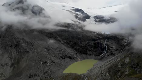 Aerial-flyover-from-Lagh-da-Caralin-glacial-lake-underneath-Palu-glacier-on-a-cloudy-day-in-the-Swiss-Alps-near-Engadin