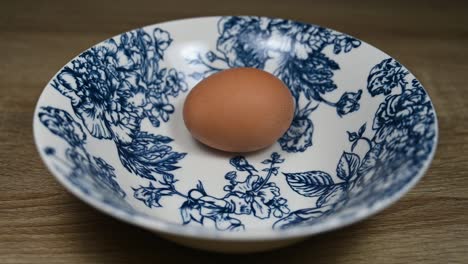 Egg-in-an-elaborately-designed-ceramic-bowl-moving-while-the-camera-zooms-out