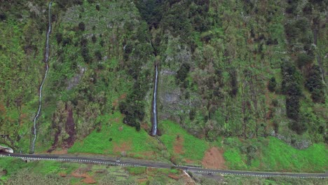 Drone-flying-away-from-a-waterfall-near-the-Atlantic-ocean-coastline-in-Madeira-island