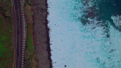 Aerial-view-of-Madeira-island-coastline,-birdseye-view-tilting-up-and-moving-backwards