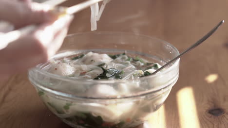 Nahaufnahme-Von-Fleischbällchen-Und-Reisnudeln-Aus-Einer-Sehr-Heißen-Asiatischen-Suppe-Mit-Stäbchen-Greifen-Und-Essen