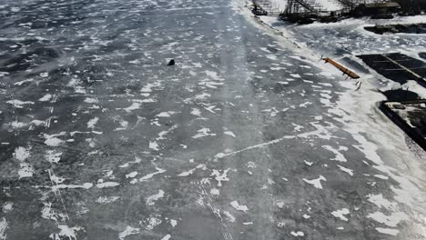 Tilting-up-from-birdseye-view-of-the-deep-ice-in-mid-February-to-the-surrounding-lakeshore-of-Muskegon-Lake
