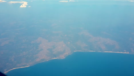 Hazy-view-from-airplane-window-over-coastline