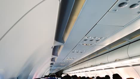 Cabin-of-an-airplane-during-take-off-showing-seated-passengers,-with-seatbelt-sign-on
