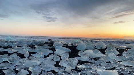 Fixed-panoramic-ground-level-shot-of-the-sunset-with-glacial-ice-on-the-foreground-of-Diamond-Beach-in-South-Iceland