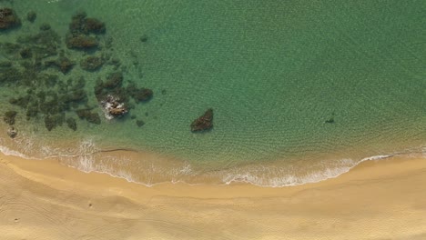 Luftaufnahme-Von-Oben-Nach-Unten-Sanfte-Wellen,-Die-In-Einen-Wunderschönen-Strand-Mit-Goldenem-Sand-Rollen