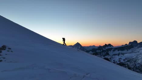 Female-mountaineer-climbing-a-mountain-with-skis-before-sunrise