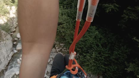 Point-of-view-to-a-canyon-river,-slacklining-from-a-high-rope