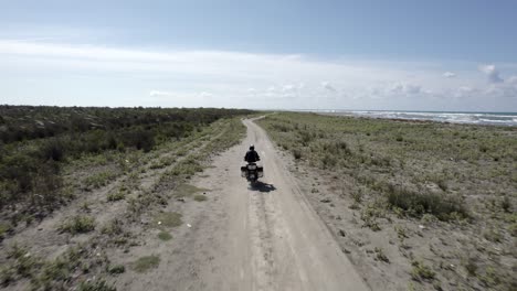 Video-Mit-Drohne-„follow-Me“-Zu-Einem-Am-Strand-Entlang-Fahrenden-Motorradfahrer
