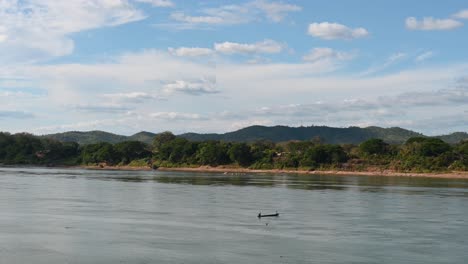 Un-Barco-De-Pesca-A-La-Deriva-Por-El-Río-Mekong,-Tailandia-Y-Laos