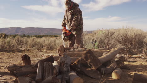 Ein-Mann-In-Jagdausrüstung-Benutzt-Eine-Kettensäge,-Um-Brennholz-Zu-Zerkleinern